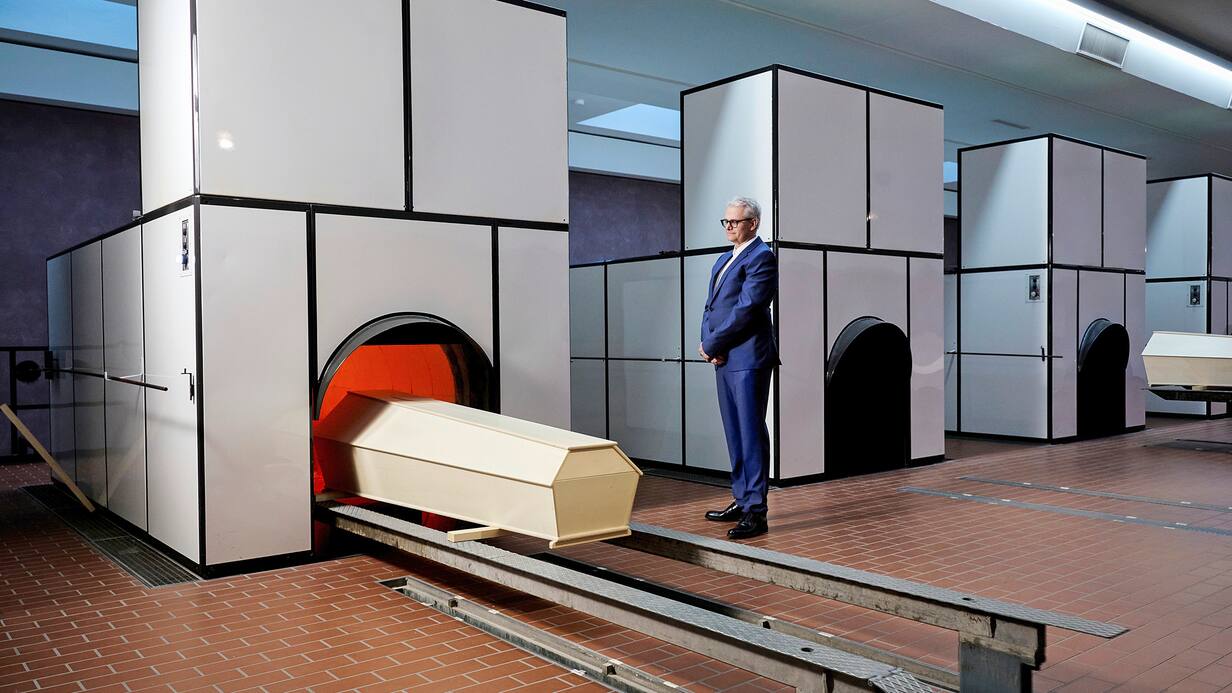 Dans la salle des fours, Andreas Bichler surveille l’entrée d’un cercueil vide. Pour les mises en scène, il troque ses vêtements de travail contre un costume.