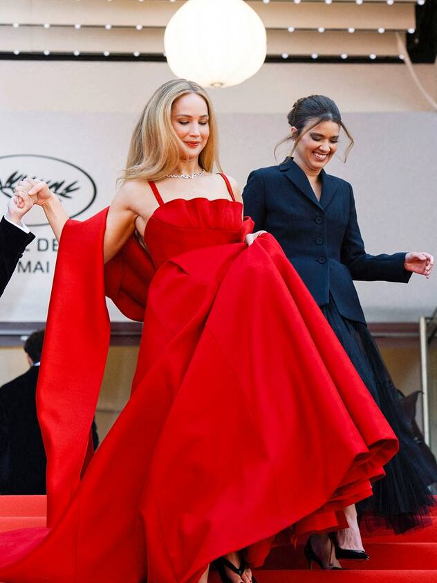 Jennifer Lawrence foule le tapis rouge dans une robe Dior rouge et des tongs noires en arrivant à la première d'Anatomie d'une Chute dans le cadre du 76e Festival de Cannes à Cannes, France, le 21 mai 2023. 