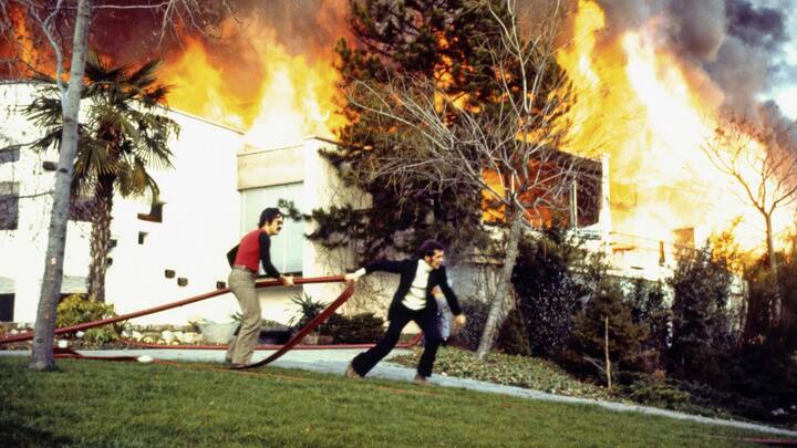 Le 4 décembre 1971, après le geste d’un inconscient, une fusée de détresse tirée pendant le concert des Mothers of Invention de Frank Zappa, le Casino de Montreux – dont le toit est en roseau – est ravagé par les flammes. Claude Nobs (à g.) et Jean-Paul Marquis, responsable de la scène le jour du drame, tirent une lance à incendie. 