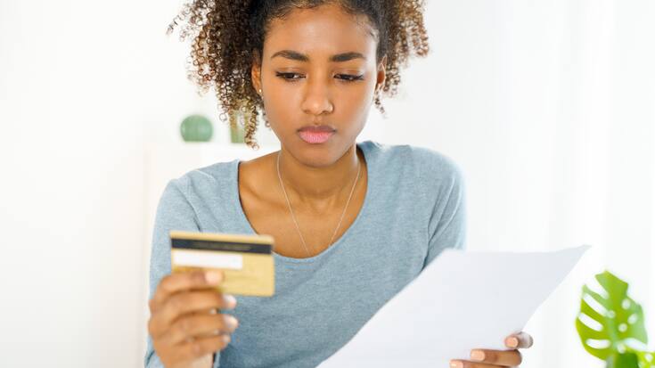 femme dubitative face à sa carte de crédit
