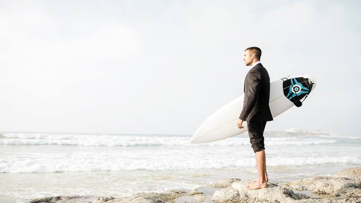 A Businessman holding is surfboard after a long day of work