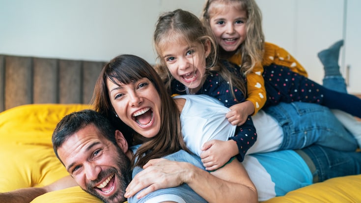 Portrait of family - mother, father and little girls twins smiling and looking at camera