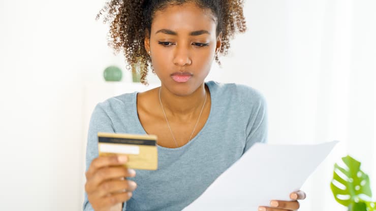 femme dubitative face à sa carte de crédit