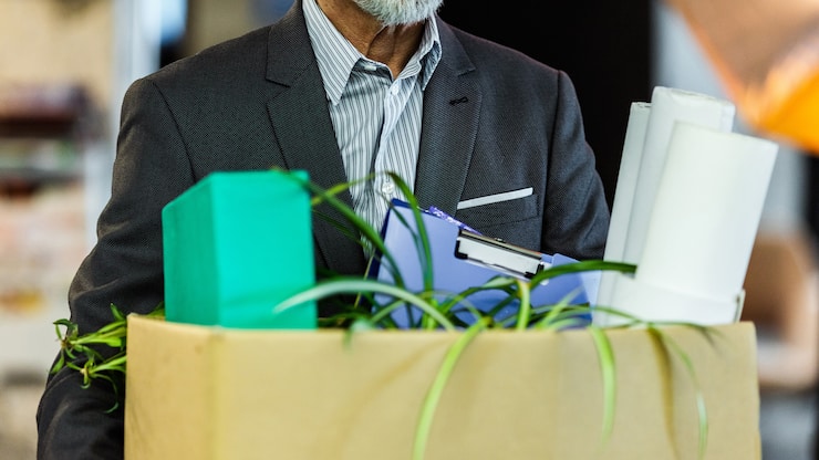 Unrecognizable male entrepreneur carrying his belongings after being fired from his job.