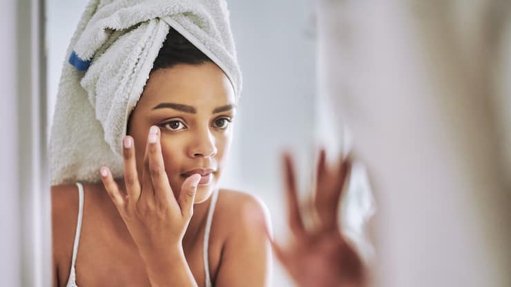 Shot of an attractive young woman looking at her face in the bathroom mirror