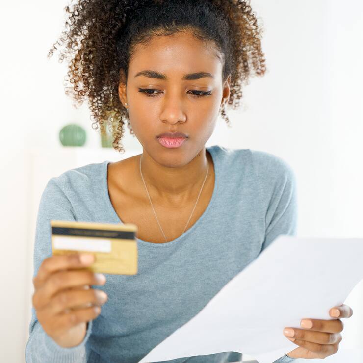 femme dubitative face à sa carte de crédit