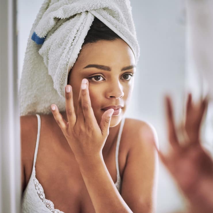 Shot of an attractive young woman looking at her face in the bathroom mirror