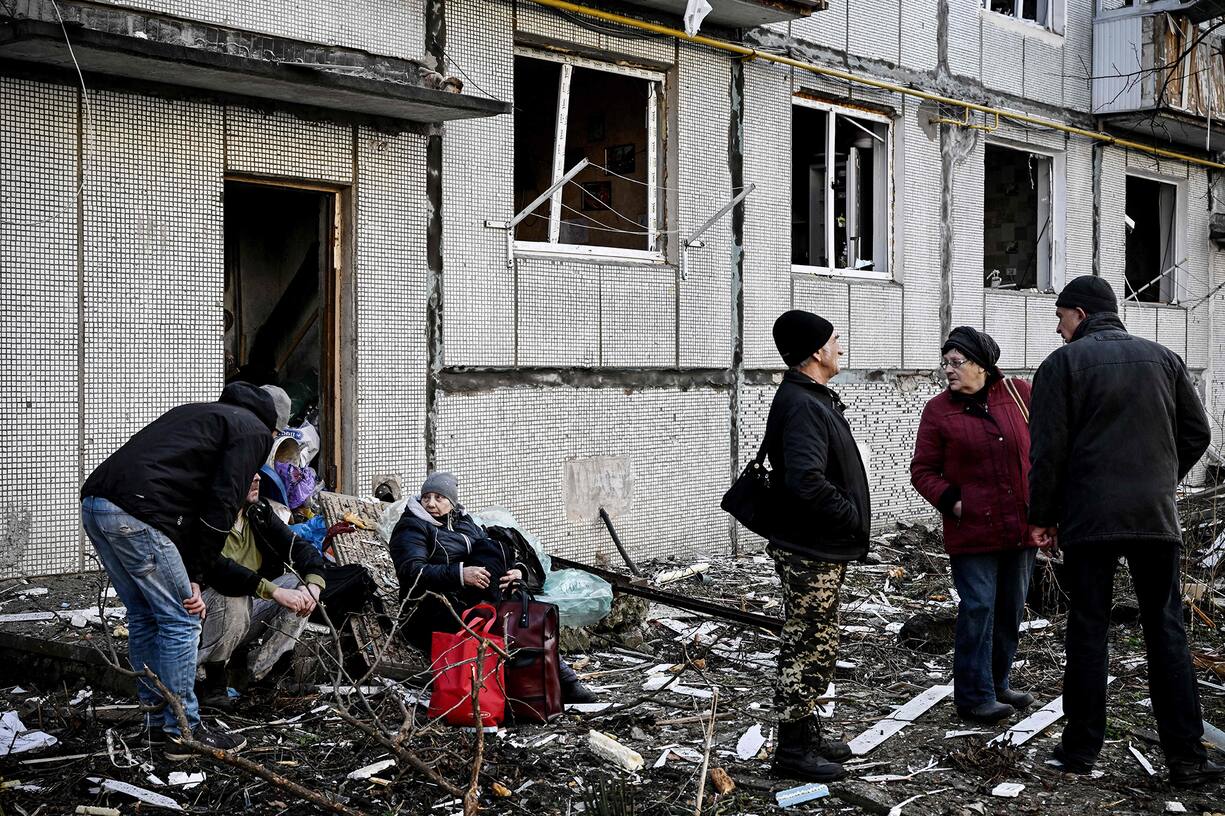 Des habitants devant leur immeuble atteint par un bombardement.