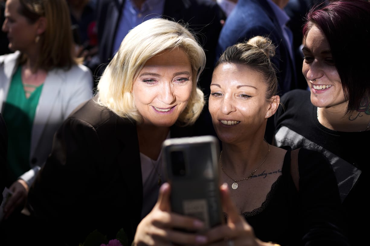 French far-right leader Marine Le Pen, left, poses for a selfie with a supporter as she campaigns in a market in Pertuis, southern France, Friday, April 15, 2022. (AP Photo/Daniel Cole)Marine Le Pen