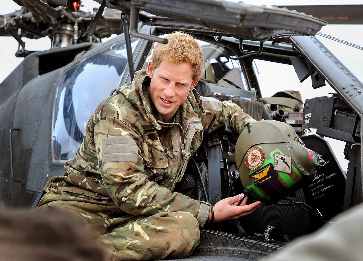 Dans cette image publiée le 21 janvier 2013, le Prince Harry, montre à une équipe de télévision son casque de vol alors qu'il effectue des vérifications matinales en étant assis sur un hélicoptère Apache sur la ligne de vol contrôlée par les Britanniques à Camp Bastion le 12 décembre 2012 en Afghanistan. Le Prince Harry a servi en tant que pilote/gunner d'hélicoptère Apache au sein du 662 Sqd Army Air Corps, de septembre 2012 pour quatre mois jusqu'en janvier 2013. 