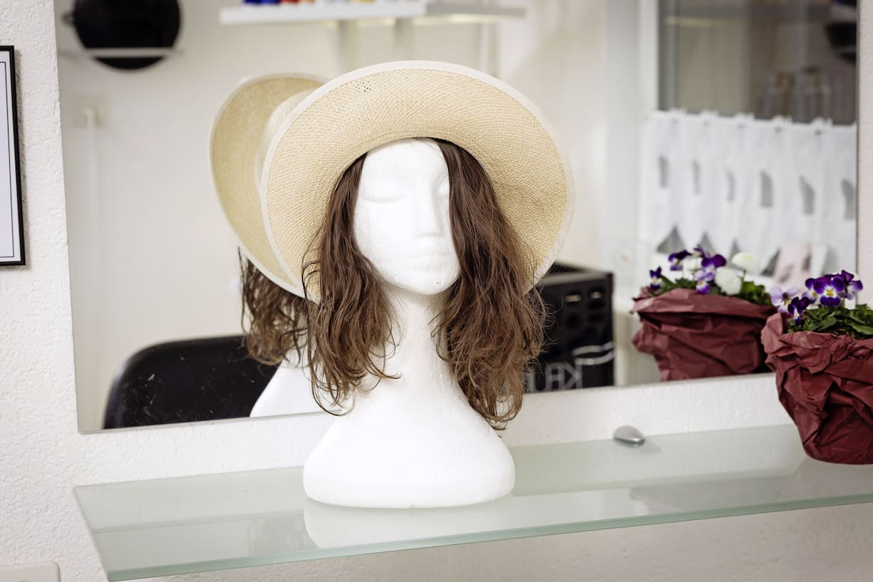 La «pascalette»,  une perruque confectionnée par Pascale Burri, permettant d’associer les cheveux coupés, collés sur un fin bandeau, à un accessoire type foulard ou, comme ici, à un chapeau.