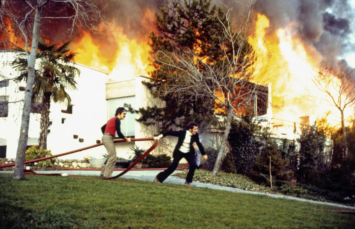 Le 4 décembre 1971, après le geste d’un inconscient, une fusée de détresse tirée pendant le concert des Mothers of Invention de Frank Zappa, le Casino de Montreux – dont le toit est en roseau – est ravagé par les flammes. Claude Nobs (à g.) et Jean-Paul Marquis, responsable de la scène le jour du drame, tirent une lance à incendie. 