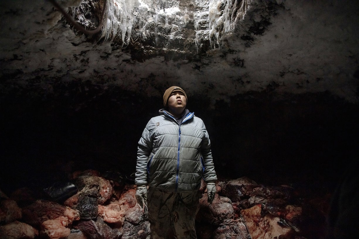 Un homme range des morceaux de viande de baleine dans sa cave à glace