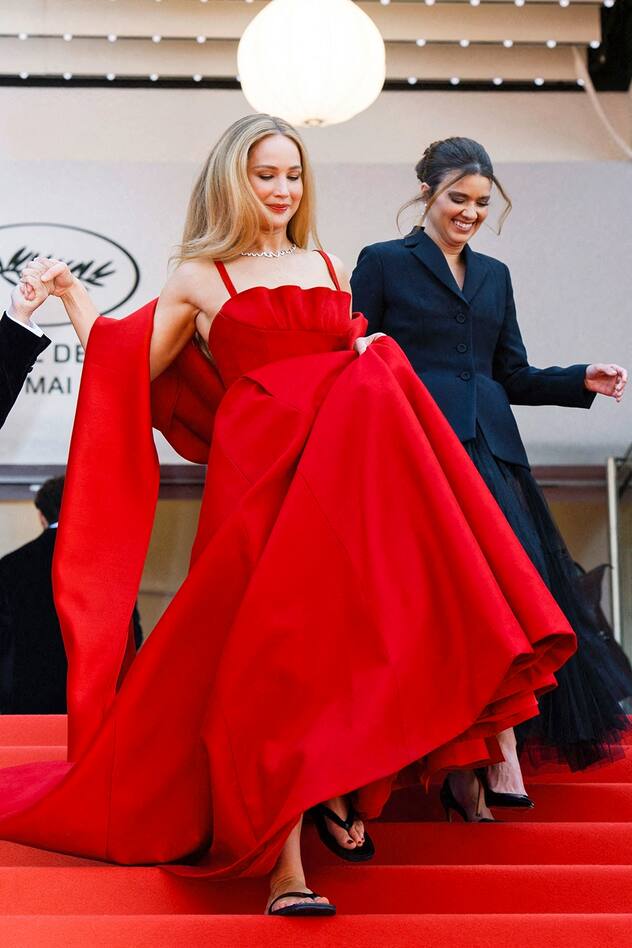 Jennifer Lawrence foule le tapis rouge dans une robe Dior rouge et des tongs noires en arrivant à la première d'Anatomie d'une Chute dans le cadre du 76e Festival de Cannes à Cannes, France, le 21 mai 2023.