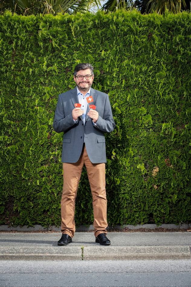 Kevin Grangier tenant des drapeaux suisses, clin d’œil à l’une de ses premières actions militantes lors d’Expo.02 à Bienne
