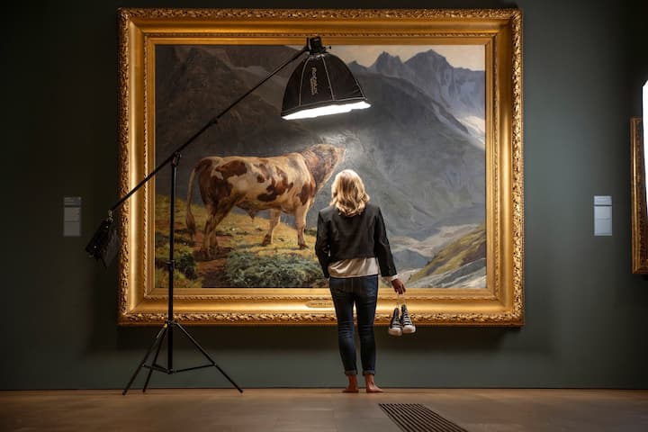 Le journaliste de la RTS Martina Chyba devant le fameux «Taureau dans les Alpes» (1884) d’Eugène Burnand