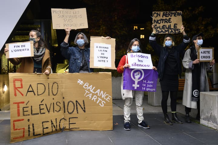 Des femmes brandissent une pancarte lors d'une action de "solidarite feministe" du mouvement "Greve feministe Vaud" suite aux accusations d'harcelement sexuel au sein de la RTS dont  par son ancien presentateur vedette Darius Rochebin ce lundi 2 novembre 2020 devant le siege de la Radio Television Suisse, RTS. (KEYSTONE/Laurent Gillieron)