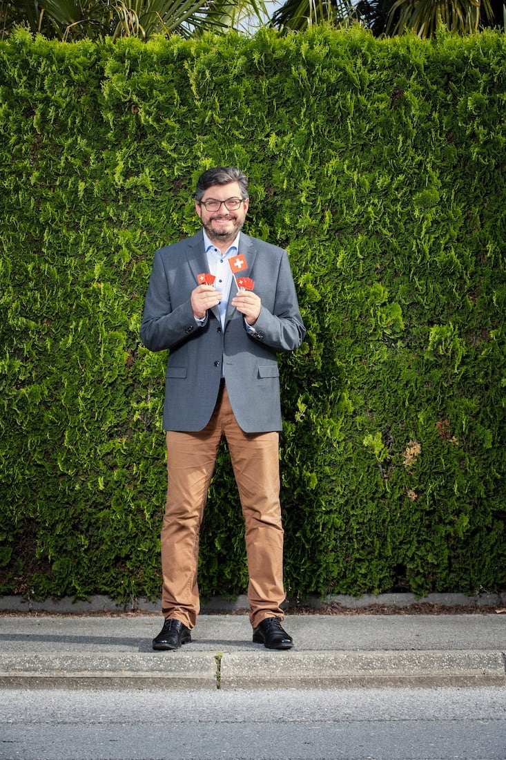 Kevin Grangier tenant des drapeaux suisses, clin d’œil à l’une de ses premières actions militantes lors d’Expo.02 à Bienne